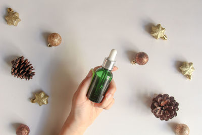 Cropped hand holding christmas decorations on white background