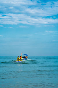 Rear view of people on boat in sea against sky