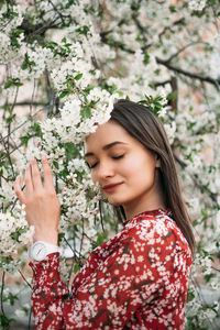 Beautiful young woman standing by flowering plants