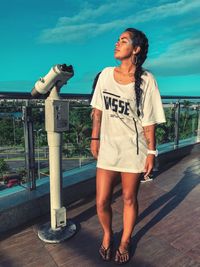 Full length of woman standing on railing against sky