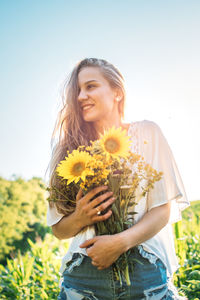 Happy woman with arms raised standing on land against clear sky