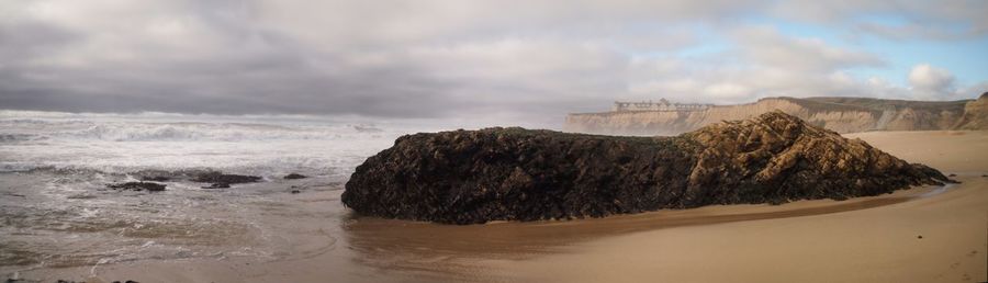 View of rocky beach against cloudy sky