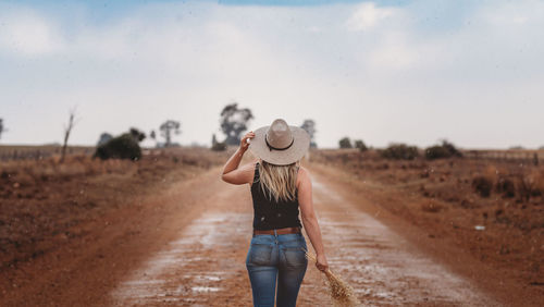 Rear view of man standing on dirt road