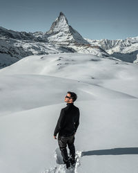 Rear view of man standing on snow covered mountains