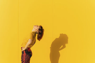 Digital composite image of woman standing against yellow wall