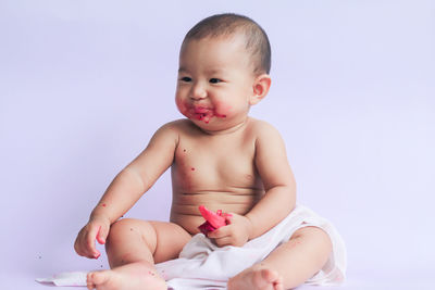 Cute baby girl sitting against gray background