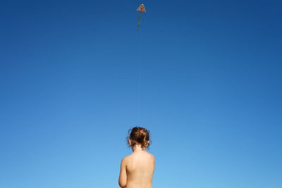 Rear view of young girl against clear blue sky