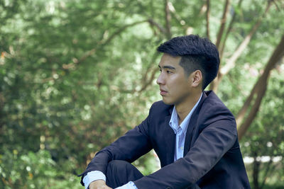 Young man looking away in forest