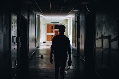 Rear view of silhouette man walking in corridor