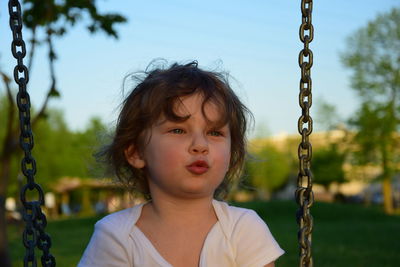 Cute girl looking away on swing at playground