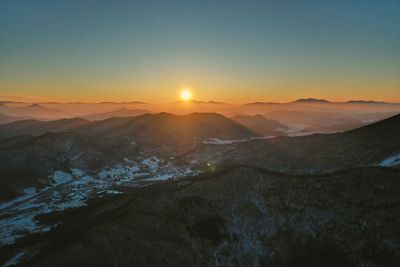 Scenic view of snowcapped mountains against clear sky during sunset