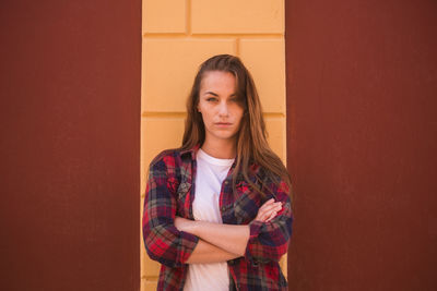 Portrait of confident woman standing against wall