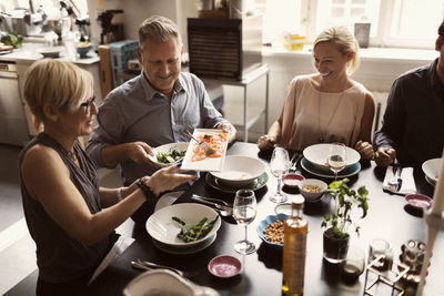 Happy friends enjoying food while sitting at table