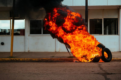 Burning vehicle on road against building