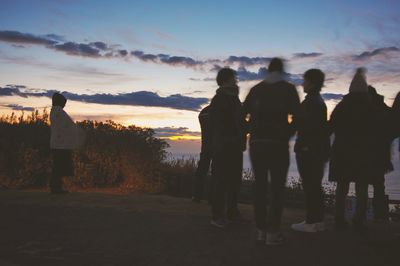 Silhouette people standing on mountain against sky during sunset