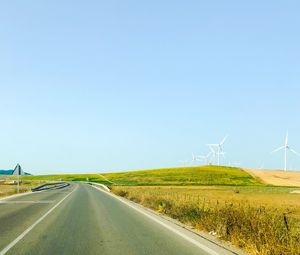 Diminishing perspective of empty road amidst field against clear sky