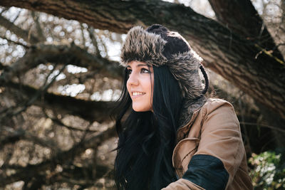 Portrait of smiling young woman against tree