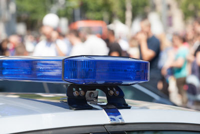 Close-up of police car with people in background