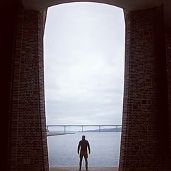 Silhouette man standing at sea against sky