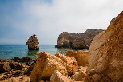 Rocks on shore by sea against sky