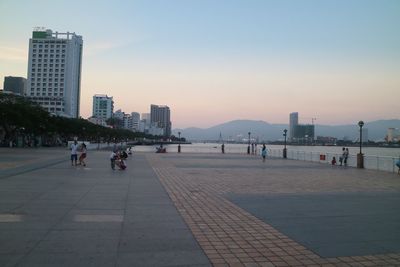 People at beach in city against clear sky