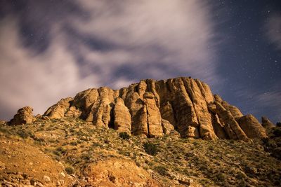 Low angle view of rocky mountains against star field at dusk