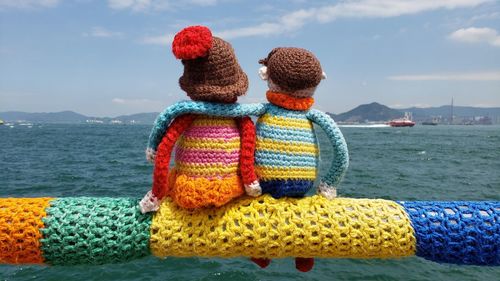 Woolen toys on railing by sea