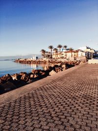 Buildings by sea against clear sky