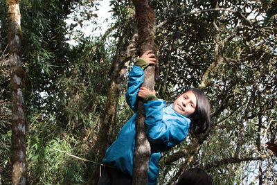 Portrait of boy climbing on tree in forest