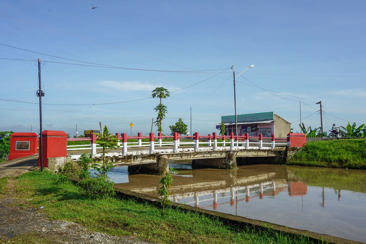 water, sky, cable, nature, electricity, architecture, transport, plant, built structure, transportation, power line, waterway, day, river, electricity pylon, no people, technology, building exterior, grass, power generation, mode of transportation, outdoors, reflection, tree, power supply, rail transportation, city, walkway, travel