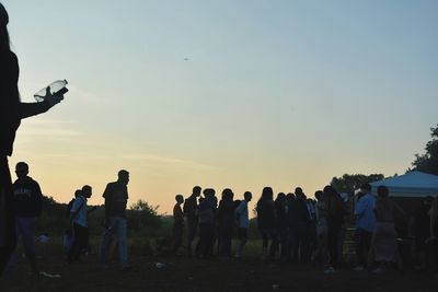 Group of people against clear sky during sunset