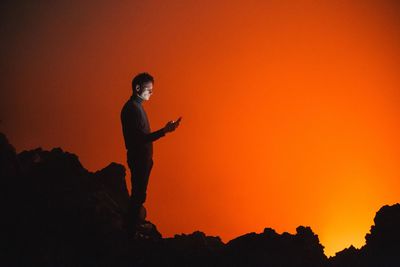 Silhouette of man using mobile phone at night