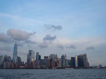 Sea by modern buildings against sky in city