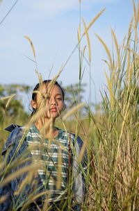 Young woman wearing mask on field against sky