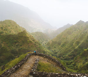 High angle view of woman standing on hill against mountains and sky