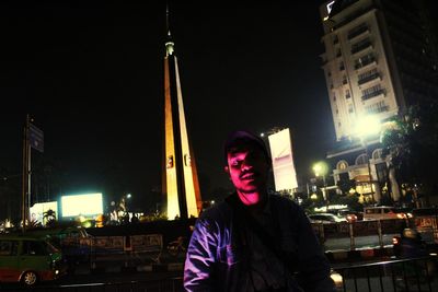 Portrait of man standing on illuminated street at night
