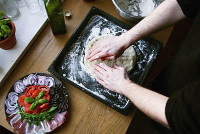 Midsection of man kneading dough