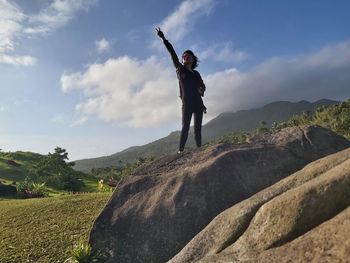 Man standing on rock against sky