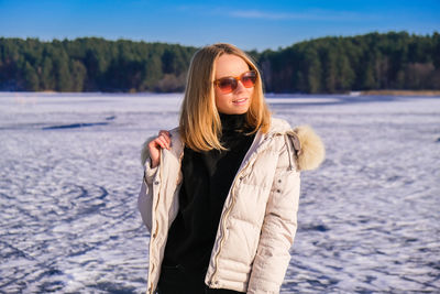 Young female smiling and away in sunglasses a snow landscape. happy hipster girl with hip hop 