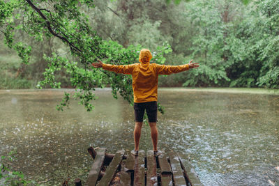 Full length of woman standing by lake during rainy season