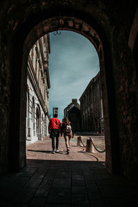 Rear view of people walking on street amidst buildings