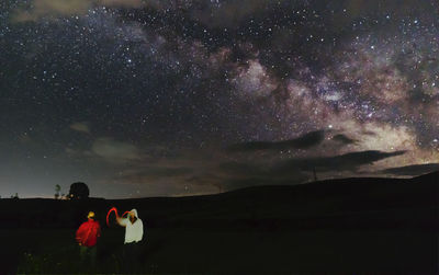 People standing on land against sky at night