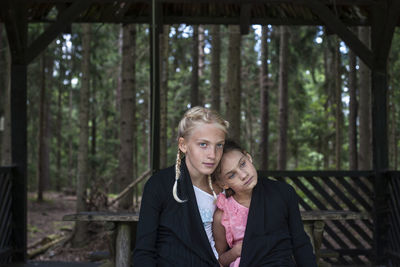 Girls sitting against trees in forest