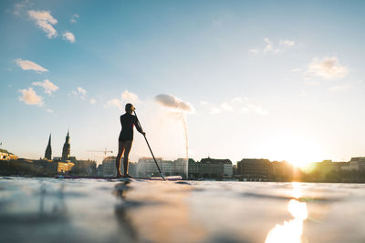 Man standing in city against sky during sunset