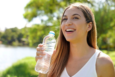 Portrait of young woman drinking water in park