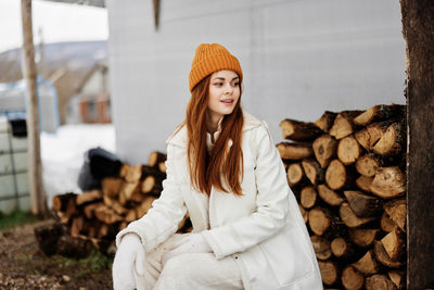 Portrait of smiling young woman standing against logs