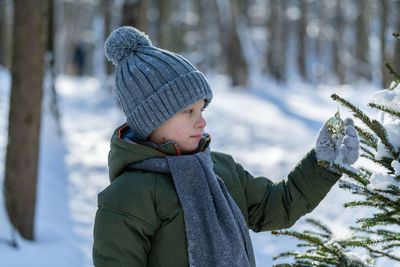 Cute boy touching plant during winter