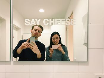 Multi ethnic friends reflecting in mirror while photographing