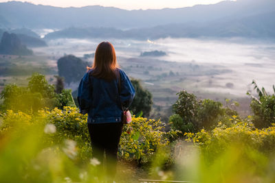 Rear view of woman standing on mountain against sky