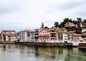 Buildings by river against sky